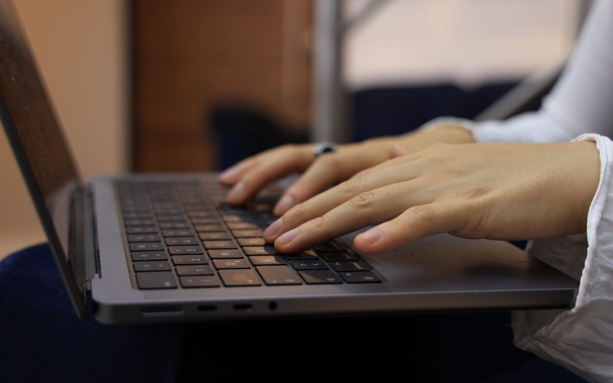 Mãos digitando no teclado de um notebook